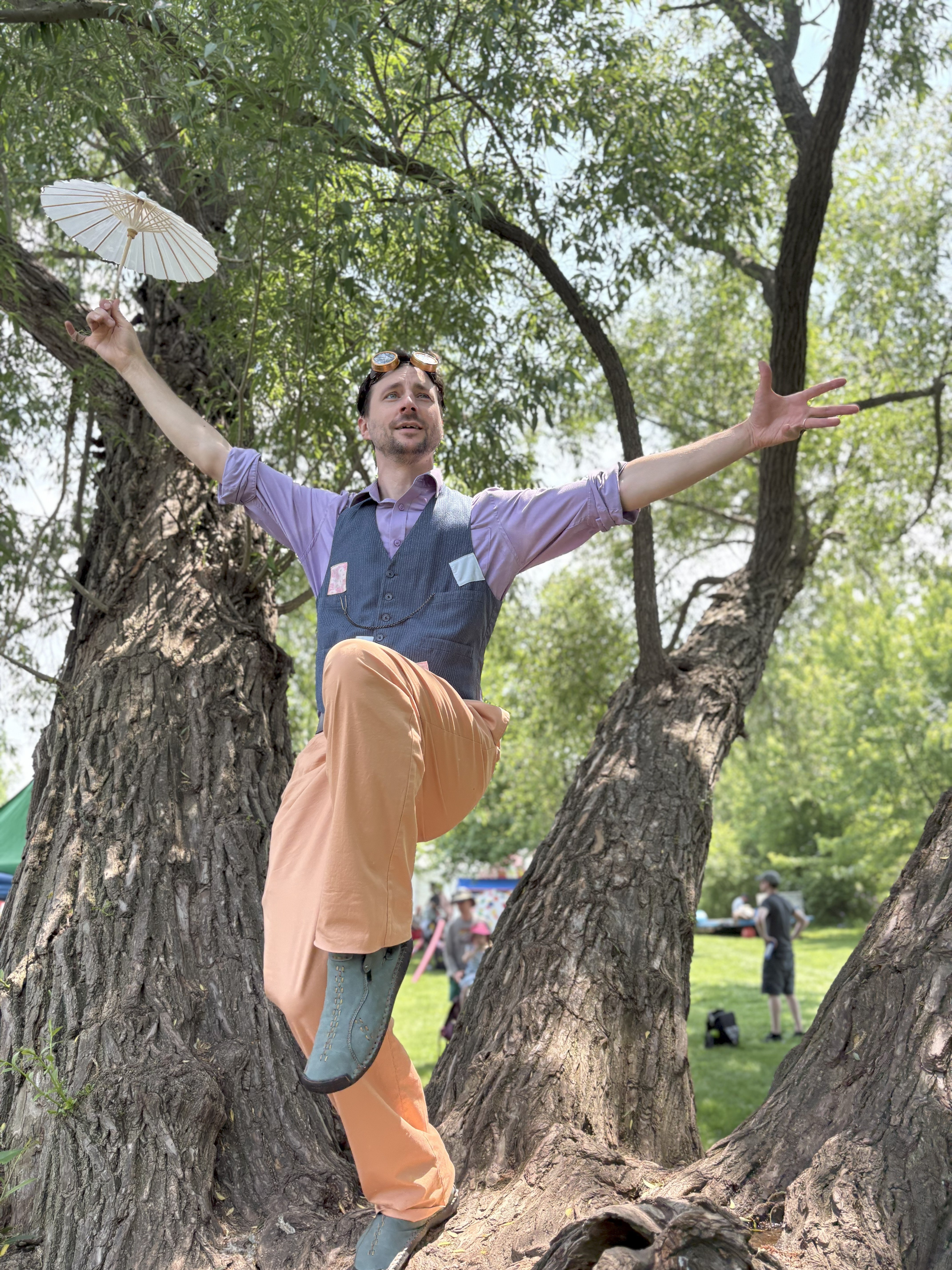 Pastel holds a tiny white umbrella while balancing on one leg on a tree.