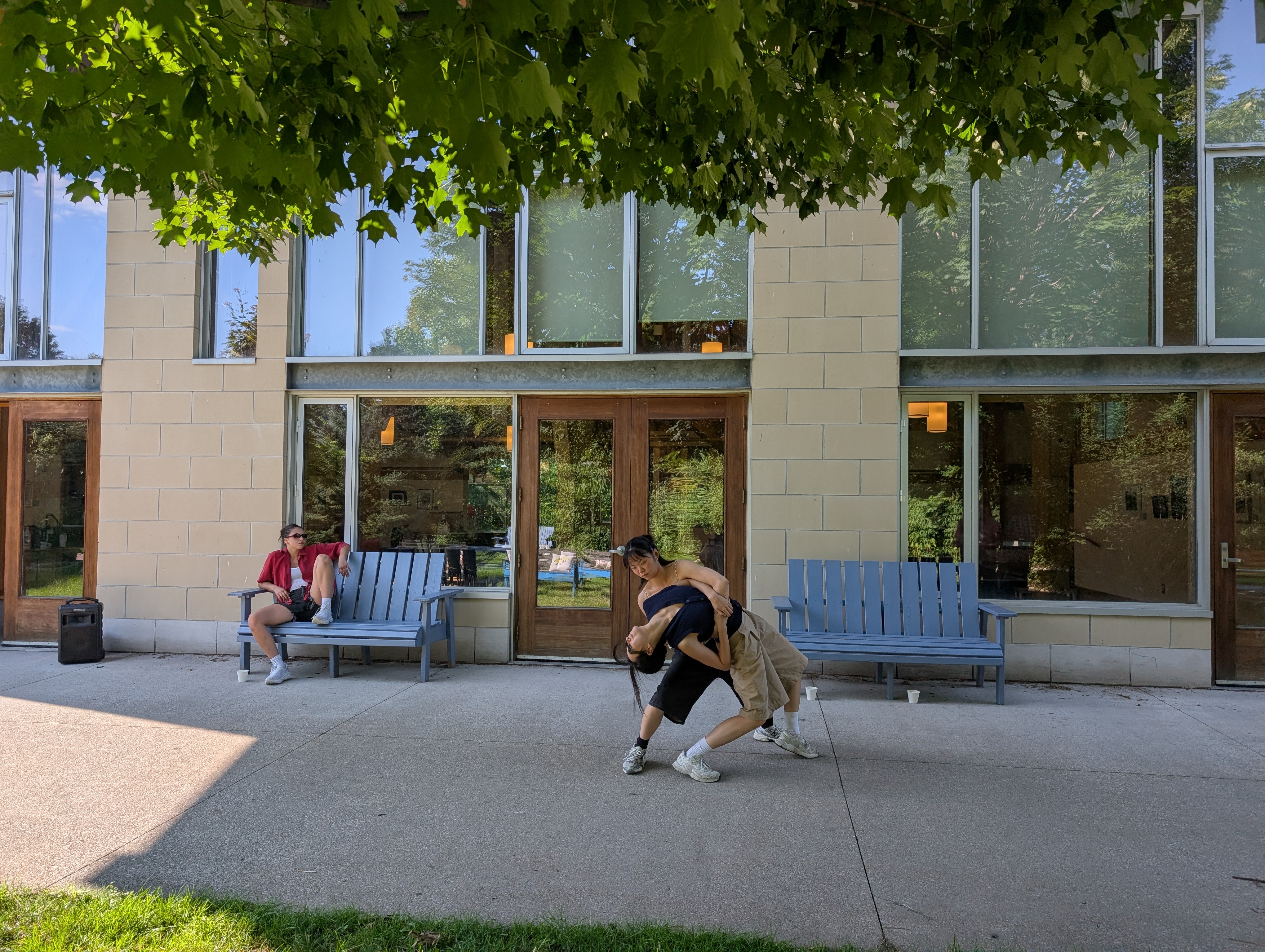two dancers dip while another looks on from a bench